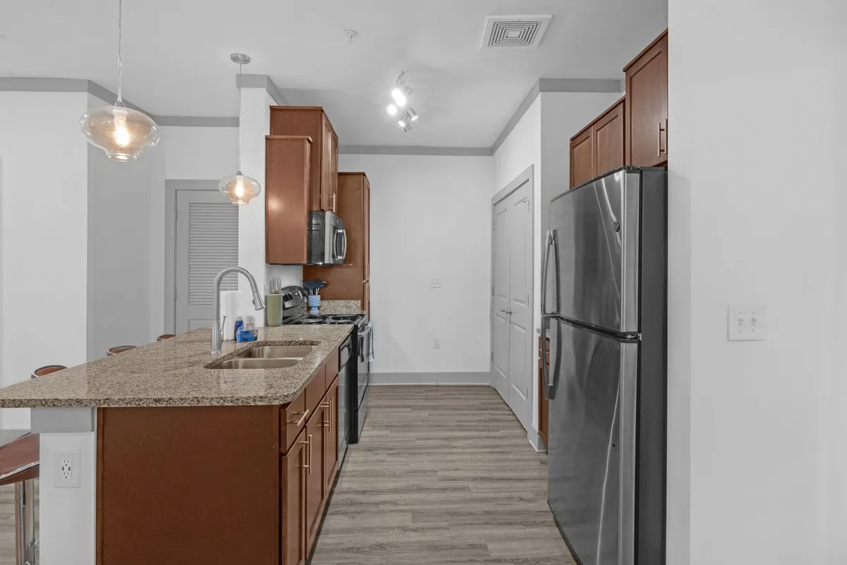 A warm, inviting kitchen featuring granite countertops, stainless steel appliances, and wood cabinetry. The space is set up for both cooking and entertaining, with ample counter space and a thoughtful layout that allows for easy movement between prep, cooking, and serving areas.