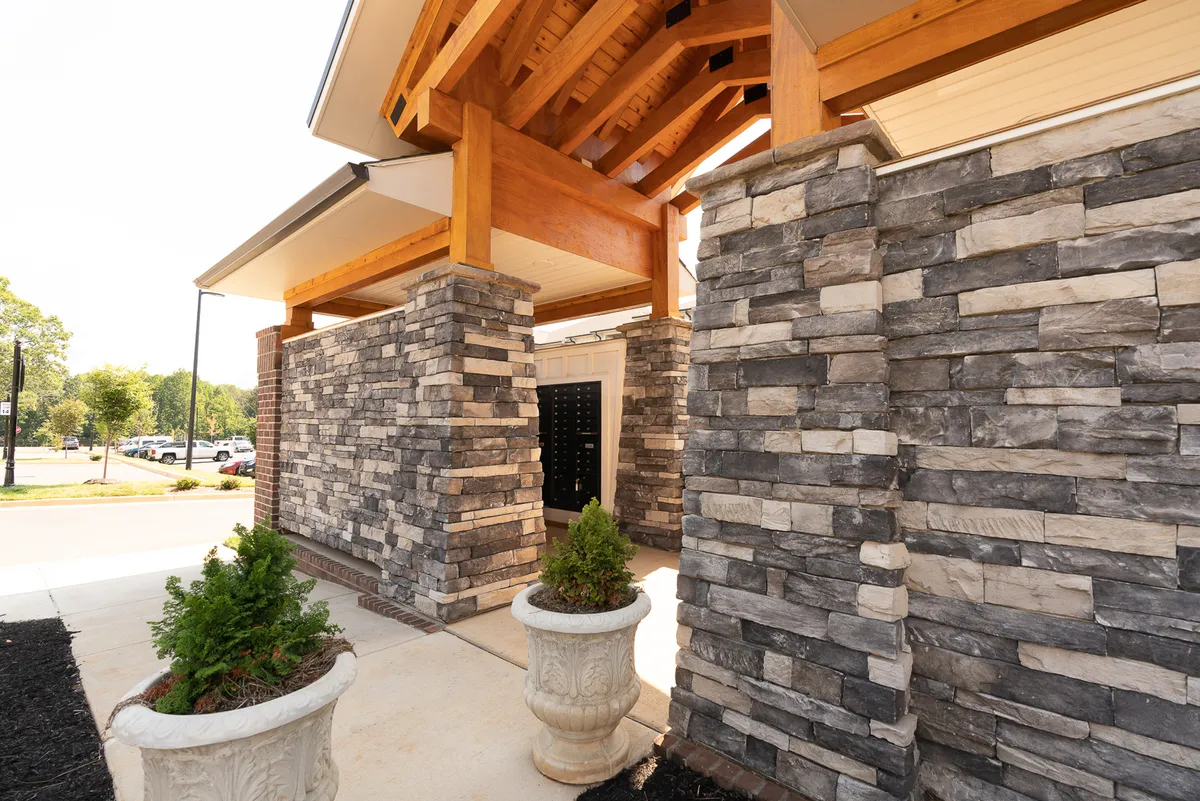 This exterior image captures the welcoming entryway of the property, showcasing elegant stone pillars, sturdy wooden beams, and lush planters. The space is bright and inviting, evoking a sense of arrival and anticipation for the adventures that await nearby.