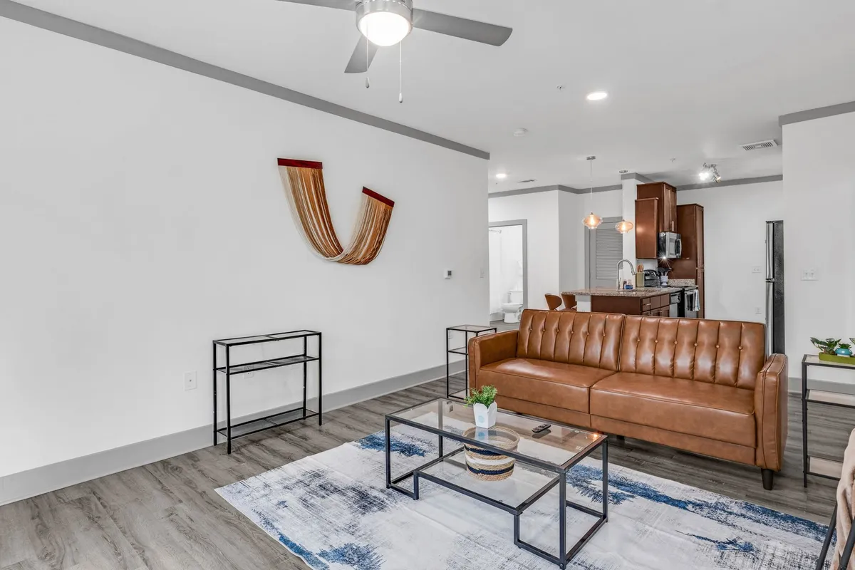 The image showcases a stylish, contemporary living room with a rich leather sofa, an eye-catching decorative wall hanging, and a modern coffee table. The space feels cozy and inviting, perfectly arranged for relaxing, reading, or socializing with friends and family.